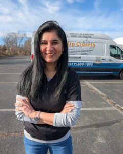 Photo of business owner, Radhika, pictured standing in front of Up Closets company van, smiling with arms crossed.